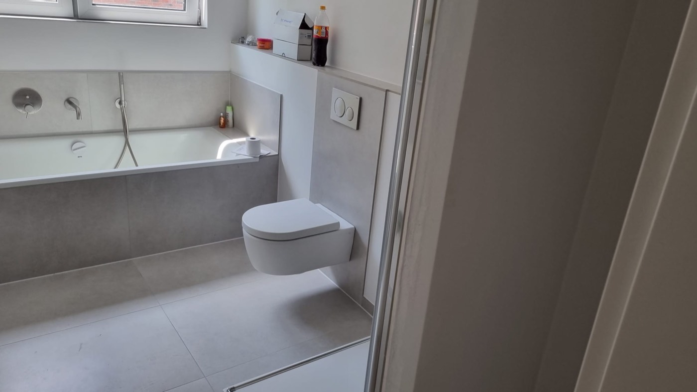 Fertige Badewanne mit grauen Großformatfliesen und Armatur