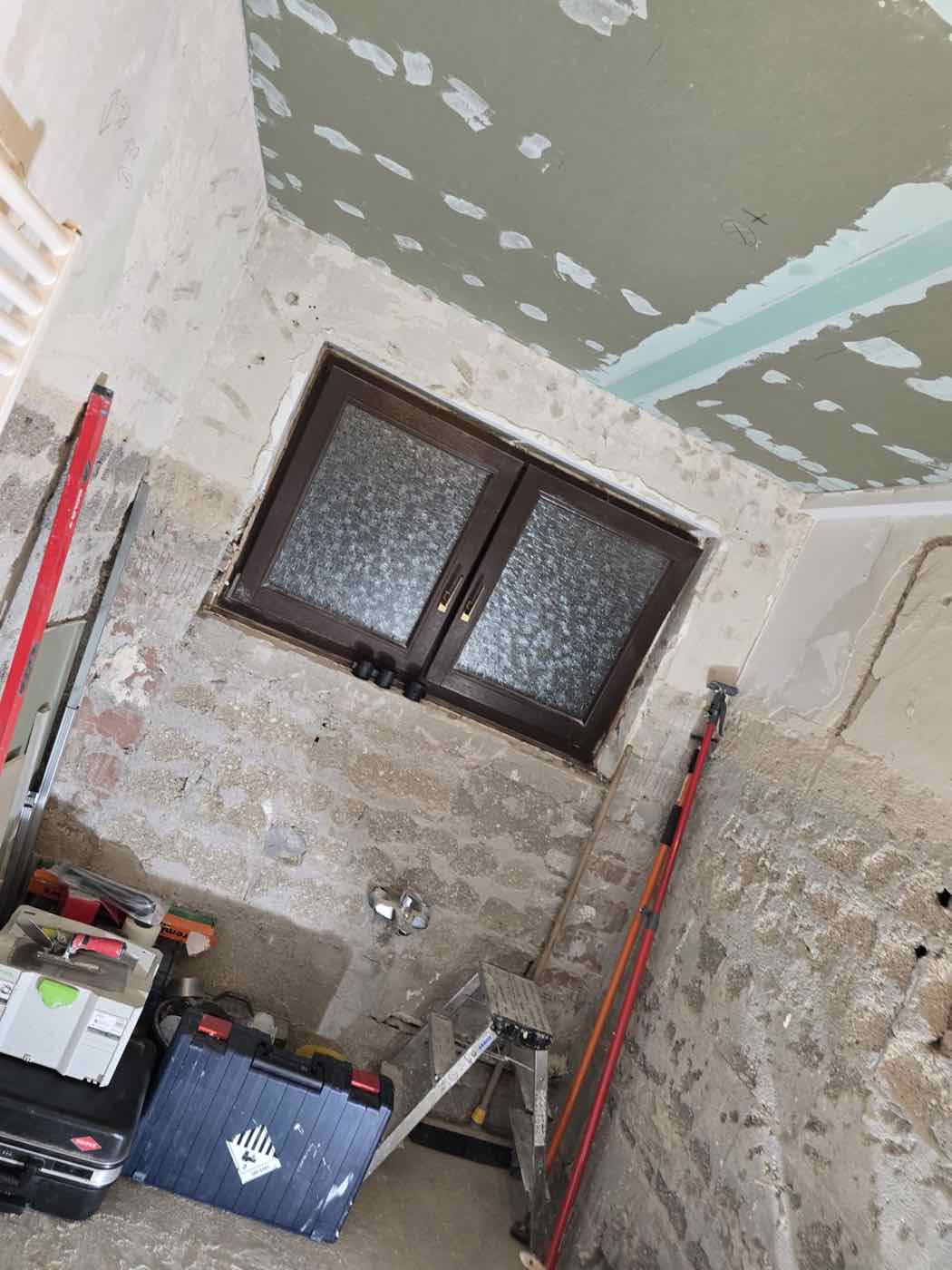 Bad im Rohbau mit altem Fenster und freigelegten Wänden